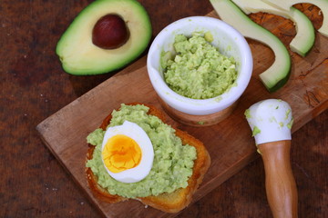 Sandwich with avocado and egg on a wooden table
