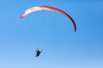 Beautiful flight of paraglider against the blue sky. Long shot of flying paraglider man. Recreational and competitive adventure sport