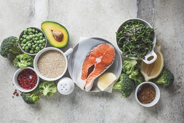 Raw salmon with broccoli, quinoa and avocado on gray background, top view. Salmon steak and...