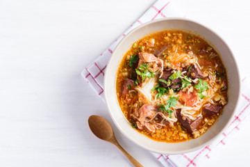 Northern Thai food (Kanom Jeen Nam Ngeaw), rice noodles with spicy soup in a bowl and spoon on white background, top view