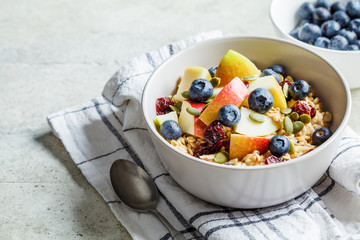 Bircher muesli or overnight oatmeal with apple, banana and blueberries in gray bowl.