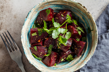 Baked beetroot salad with cilantro in bowl, top view. Healthy vegan food concept.