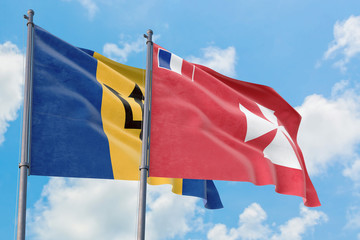 Wallis And Futuna and Barbados flags waving in the wind against white cloudy blue sky together. Diplomacy concept, international relations.