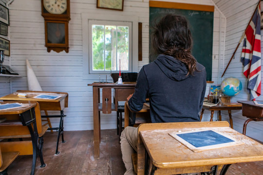 Young man sitting in the old British class of the 20th in Kootenays, British Columbia, Canada. Real school class of the 1920th. Traveling to the past
