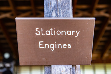 A signboard with text - stationary engines hanged on the wooden pillar in the industrial museum, Kootenays, British Columbia, Canada