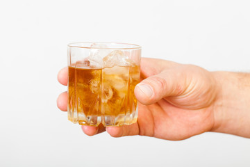 Man's hand holding a glass of whiskey on a white background