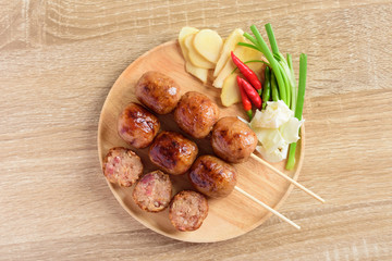 Thai sausage or Isan sausage (grilled fermented rice with pork) eating with fresh ginger, cabbage and chili peppers