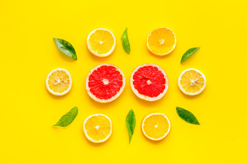 Citrus pattern. Lemon and grapefruits slices and leaves on yellow background top-down