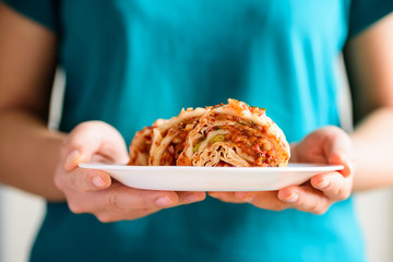 Kimchi cabbage on white plate holding by hand, Korean food