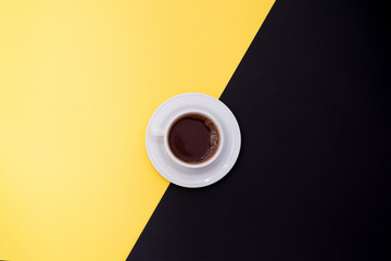 cup of fresh espresso on yellow and black background, top view with a copy space