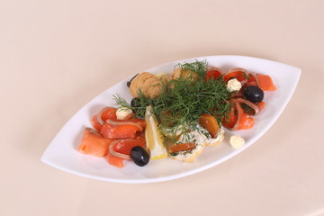 Salmon with olives and lemon on a white plate