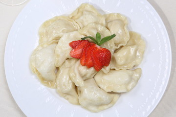 Dumplings with strawberries on a white plate