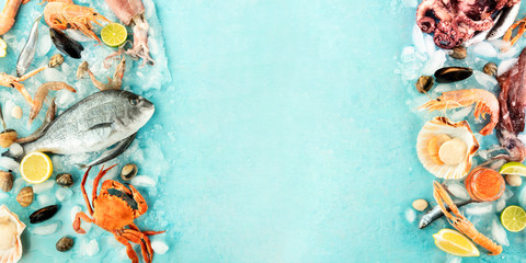 Fish and seafood variety panorama, a flat lay top shot, a frame with copy space on a blue background. Fresh fish, shrimps and prawns, crab, squid, mussels, clams, etc, on ice, a design template