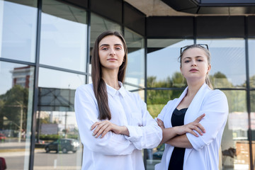 Two young business ladies negotiating near business center