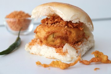 Vada pav or wada pao is a vegetarian fast food dish native to the state of Maharashtra. Famous Mumbai street food served with Red chutney and fried green chili. Copy space