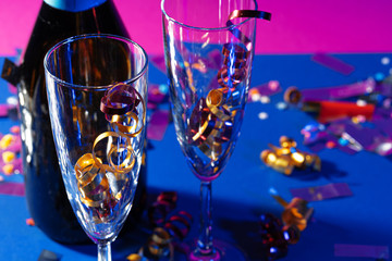 Champagne glasses with party tinsel on bright background