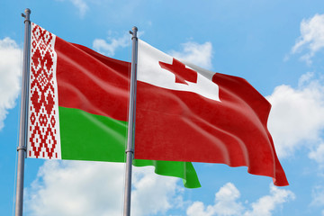 Tonga and Belarus flags waving in the wind against white cloudy blue sky together. Diplomacy concept, international relations.