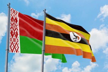 Uganda and Belarus flags waving in the wind against white cloudy blue sky together. Diplomacy concept, international relations.