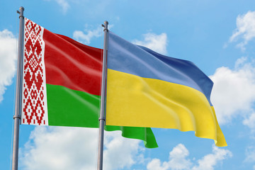 Ukraine and Belarus flags waving in the wind against white cloudy blue sky together. Diplomacy concept, international relations.