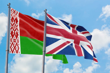 United Kingdom and Belarus flags waving in the wind against white cloudy blue sky together. Diplomacy concept, international relations.