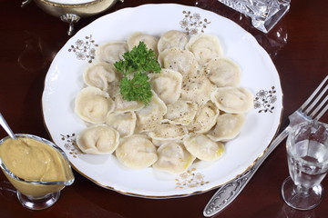 Hot Siberian dumplings with greens on a white plate