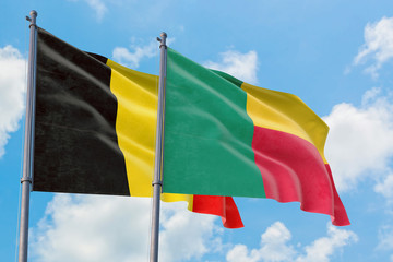 Benin and Belgium flags waving in the wind against white cloudy blue sky together. Diplomacy concept, international relations.