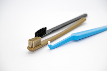 Multi-colored gold, black and blue different toothbrushes on a light background