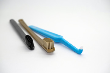 Colored gold, black and blue toothbrushes for different purposes on a light background