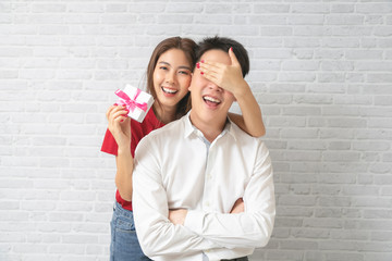 Young man receiving a surprise gift box from girlfriend at home.