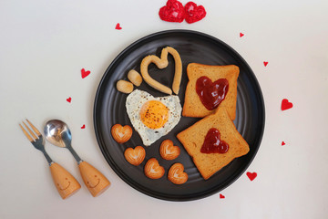 Healthy Love Breakfast on Valentine's Day - fried eggs and brown bread in the shape of a heart, chicken sausages and sweet biscuits. Top view with copy pace. Valentines day greeting.