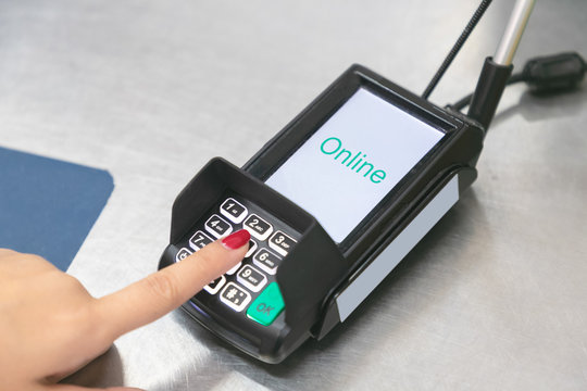 Hand of customer paying and entering security pin in credit card reader.