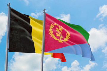 Eritrea and Belgium flags waving in the wind against white cloudy blue sky together. Diplomacy concept, international relations.