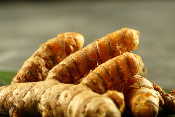 Organic fresh harvested turmeric roots on a rustic background.