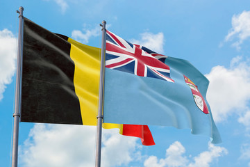 Fiji and Belgium flags waving in the wind against white cloudy blue sky together. Diplomacy concept, international relations.