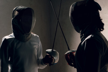Fencer woman with fencing sword. Fencers duel concept.