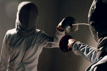 Fencer woman with fencing sword. Fencers duel concept.