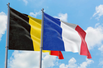 France and Belgium flags waving in the wind against white cloudy blue sky together. Diplomacy concept, international relations.