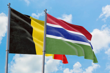 Gambia and Belgium flags waving in the wind against white cloudy blue sky together. Diplomacy concept, international relations.