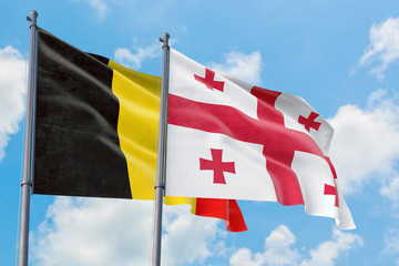 Georgia and Belgium flags waving in the wind against white cloudy blue sky together. Diplomacy concept, international relations.