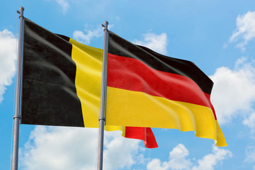 Germany and Belgium flags waving in the wind against white cloudy blue sky together. Diplomacy concept, international relations.