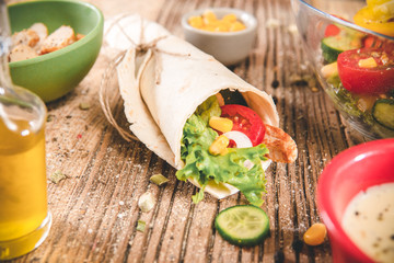 Delicious tortilla wraps on wooden table with vegetable