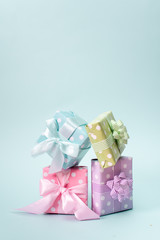 Holiday flat lay with gift boxes wrapped in colorful paper and tied with bows on blue background, decorated with confetti. Birthday, Christmas and sale concept, top view.