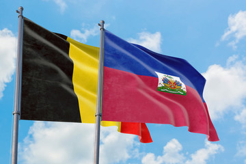 Haiti and Belgium flags waving in the wind against white cloudy blue sky together. Diplomacy concept, international relations.