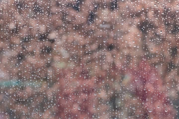 beautiful raindrops on glass window while raining with different texture with bokeh color blurred background.