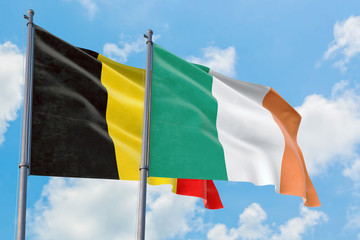 Ireland and Belgium flags waving in the wind against white cloudy blue sky together. Diplomacy concept, international relations.