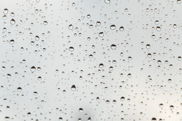 beautiful raindrops on glass window while raining with different texture with black and white colors blurred background.