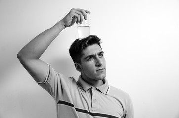 Young man looking sideways with a glass of water over his head