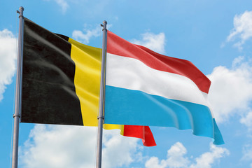 Fototapeta na wymiar Luxembourg and Belgium flags waving in the wind against white cloudy blue sky together. Diplomacy concept, international relations.