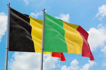 Mali and Belgium flags waving in the wind against white cloudy blue sky together. Diplomacy concept, international relations.