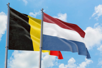 Fototapeta na wymiar Netherlands and Belgium flags waving in the wind against white cloudy blue sky together. Diplomacy concept, international relations.